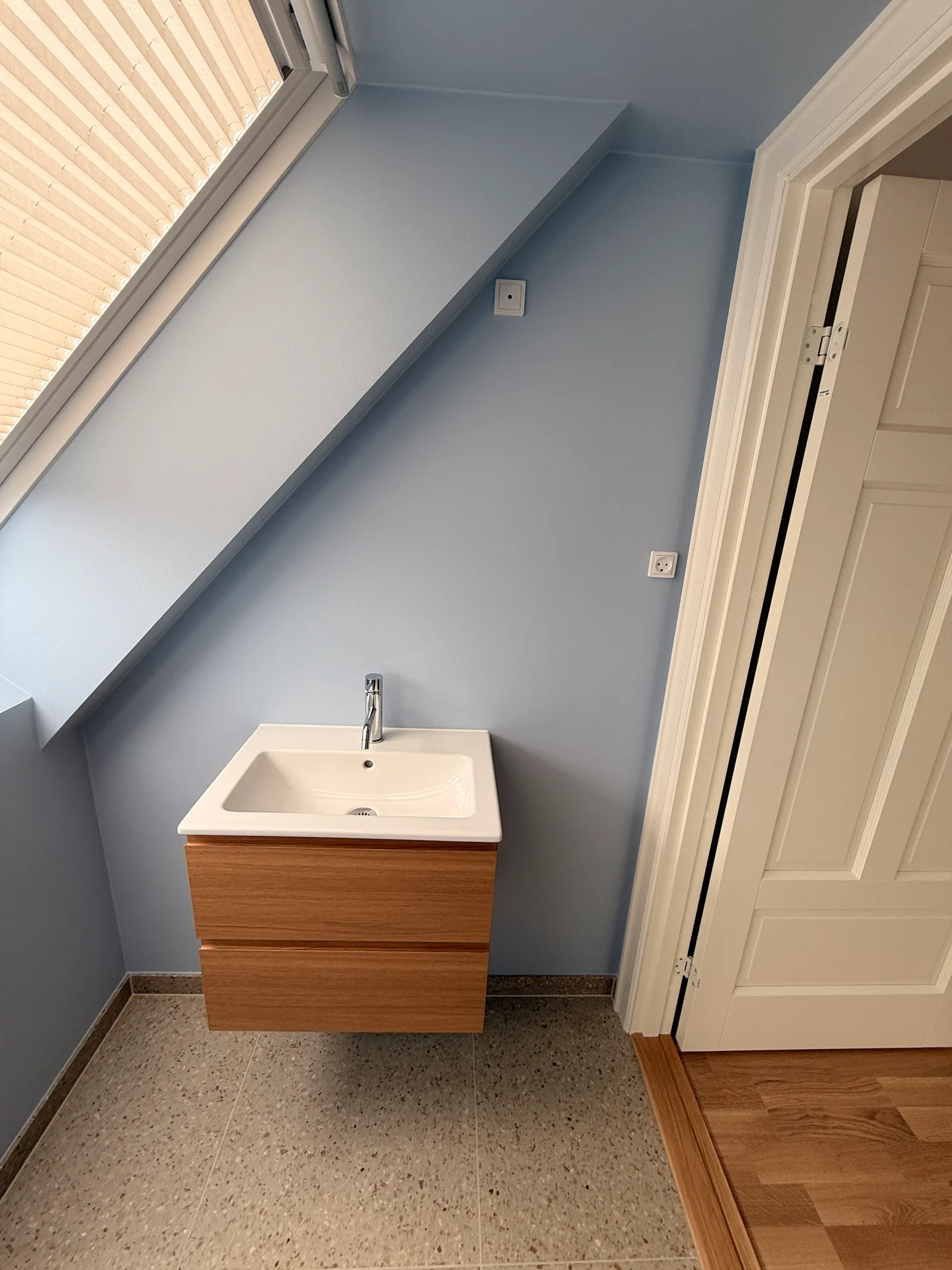 Ny 1. sal Brønshøj — toilet med håndvask på egetræsmodul, lyseblå vægge og terrazzogulv
