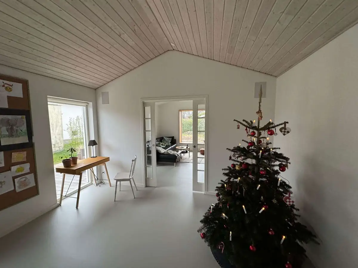 Tilbygning Amager — renoveret stue med vaulted wood-loft og juletræ